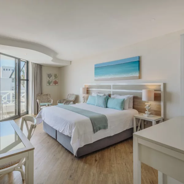 plush bed with sea colour pillows and throw, over looking the sea through large open doors