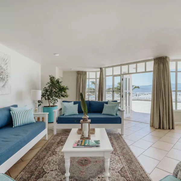 sunny hotel lounge with large plush couches, open plan onto a huge balcony, and large window offering sea views of plettenberg bay