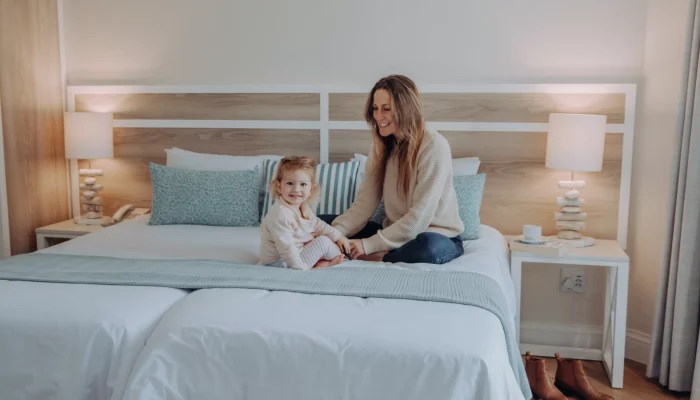 mother and daughter seated smiling on a plush hotel bed
